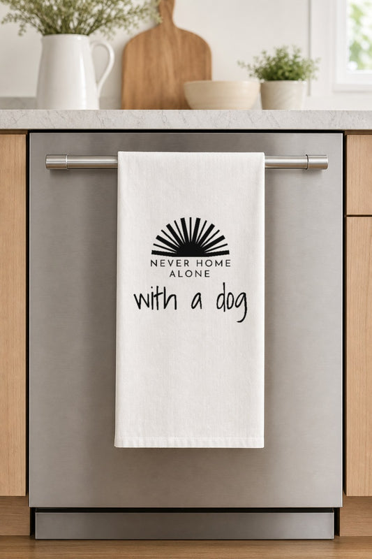 NEVER HOME ALONE with a dog hand-lettered on a white cotton flour sack tea towel